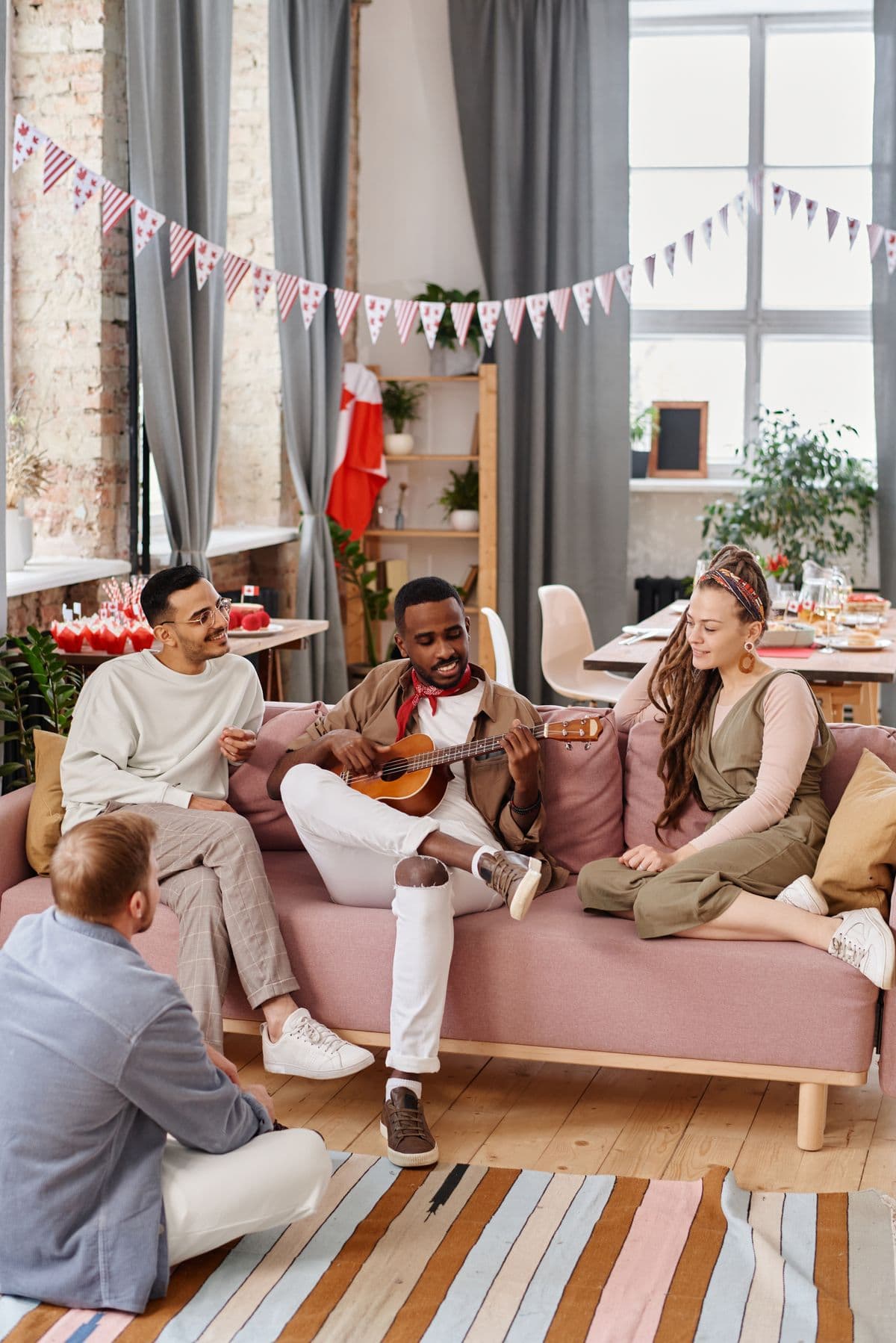 Friends spending an evening together at home, one playing guitar while the others listen and laugh
